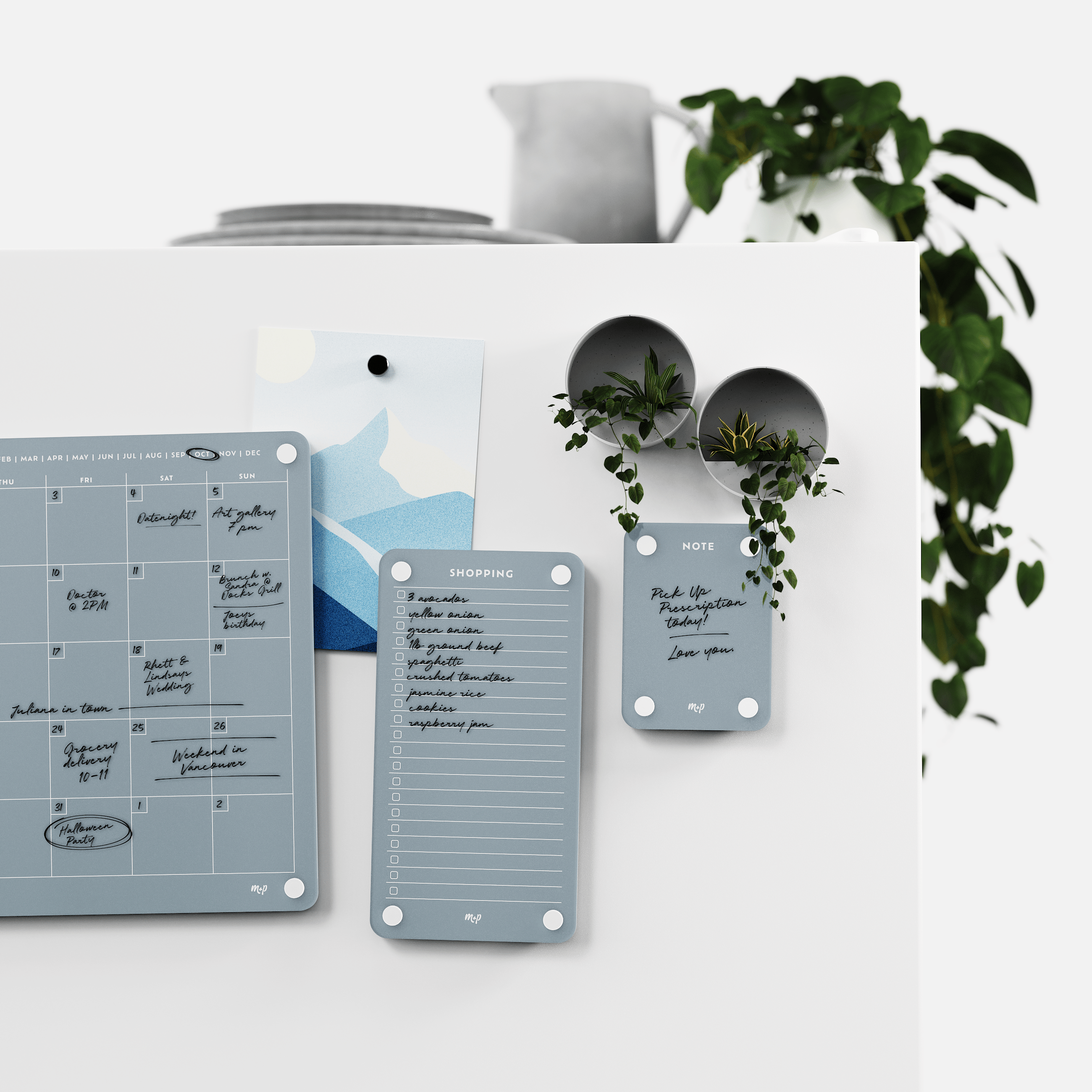 Slate grey monthly calendar, shopping list and note board on a white kitchen wall with magnetic planters